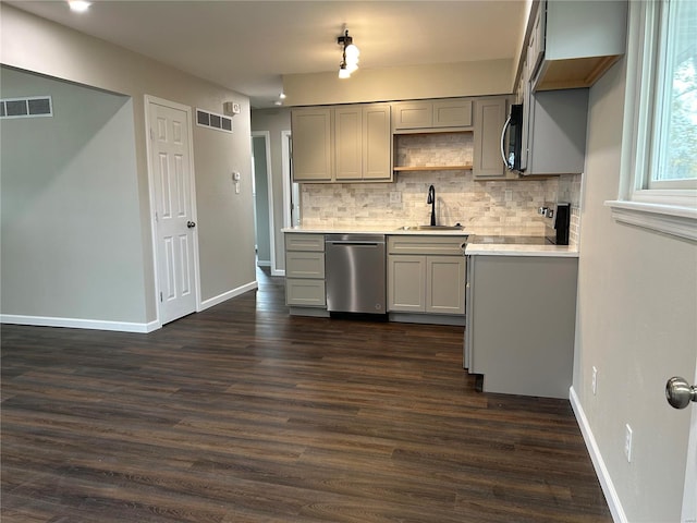 kitchen featuring backsplash, stainless steel dishwasher, sink, gray cabinets, and dark hardwood / wood-style floors