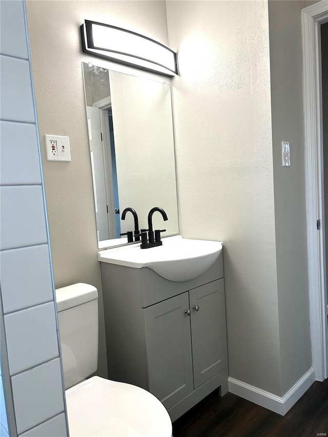 bathroom with wood-type flooring, vanity, and toilet