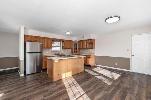 kitchen featuring backsplash, dark wood-type flooring, stainless steel refrigerator, and a kitchen island