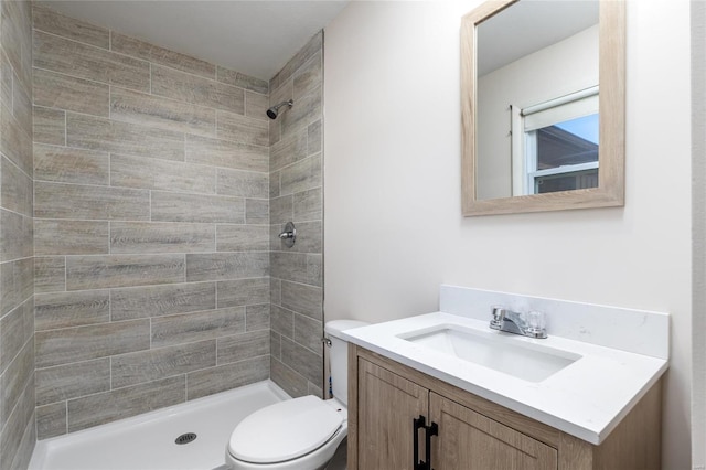 bathroom with a tile shower, vanity, and toilet