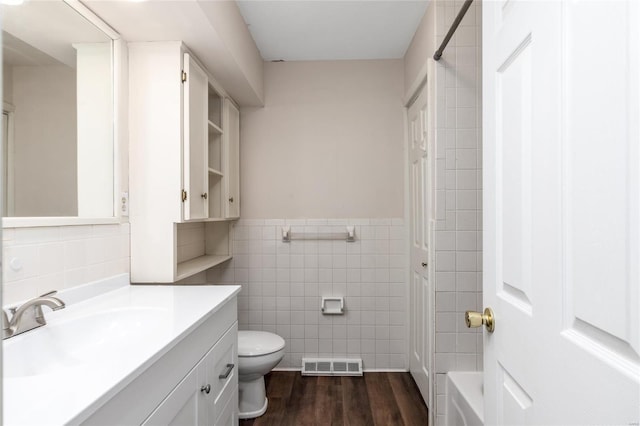 bathroom featuring vanity, hardwood / wood-style flooring, toilet, and tile walls