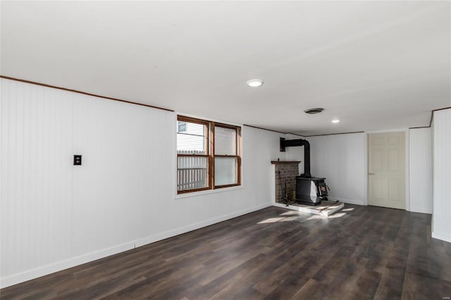 basement featuring dark hardwood / wood-style flooring and a wood stove