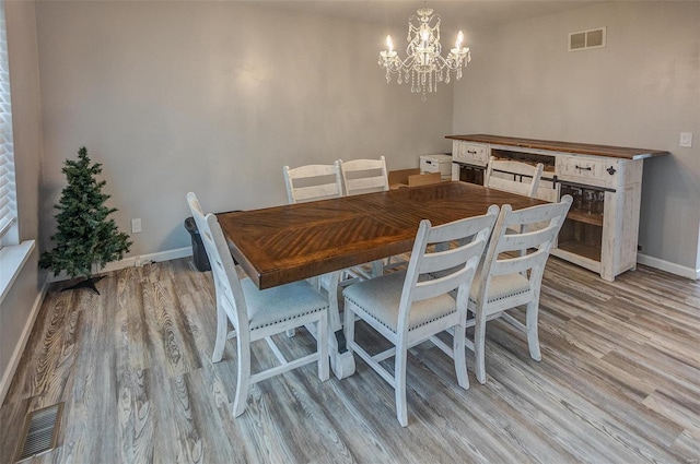 dining room with light hardwood / wood-style floors and a chandelier