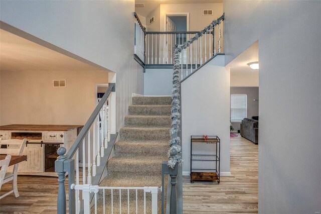 stairs with hardwood / wood-style flooring and a towering ceiling