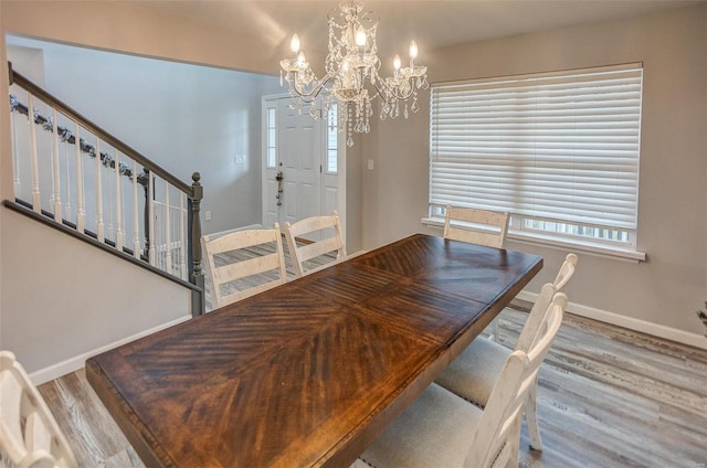 dining area with a wealth of natural light, hardwood / wood-style floors, and an inviting chandelier