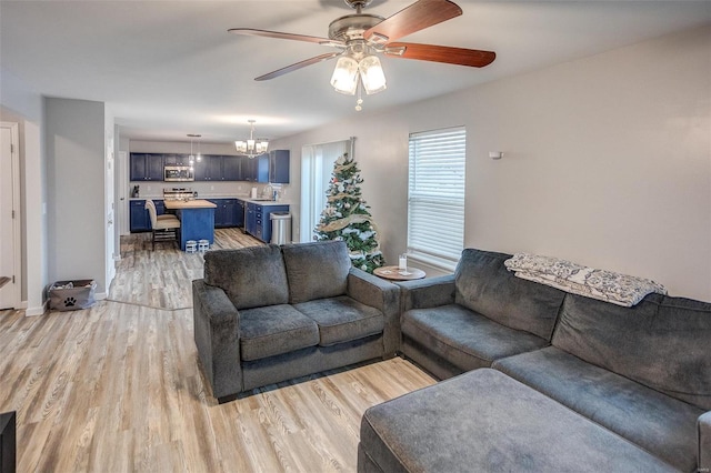 living room with sink, ceiling fan with notable chandelier, and light wood-type flooring