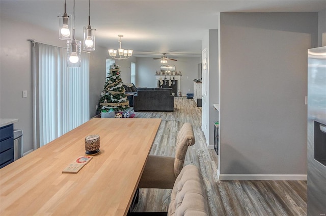 dining space featuring hardwood / wood-style flooring and ceiling fan with notable chandelier