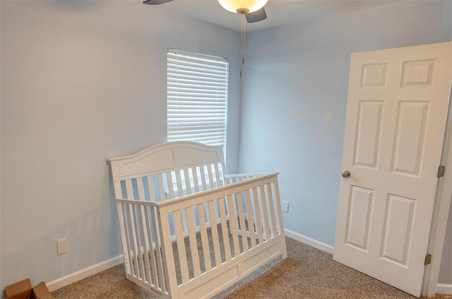 carpeted bedroom with ceiling fan and a crib