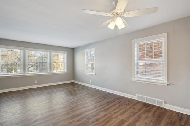 unfurnished room featuring ceiling fan, a wealth of natural light, and dark hardwood / wood-style flooring