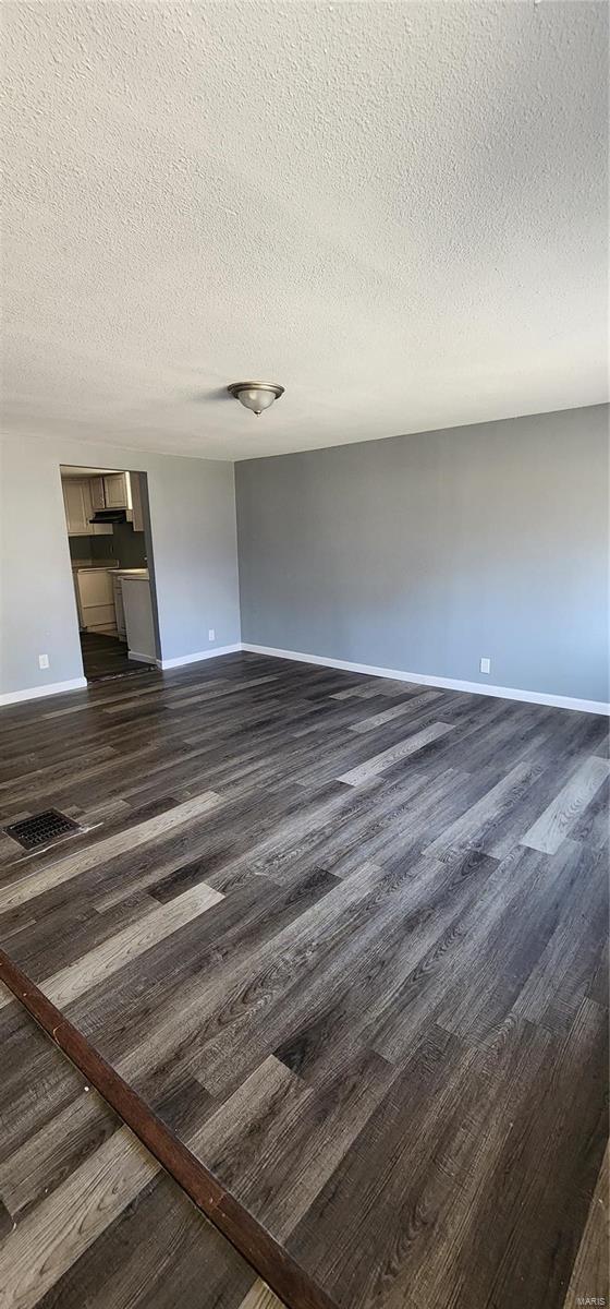 unfurnished living room with dark hardwood / wood-style floors and a textured ceiling