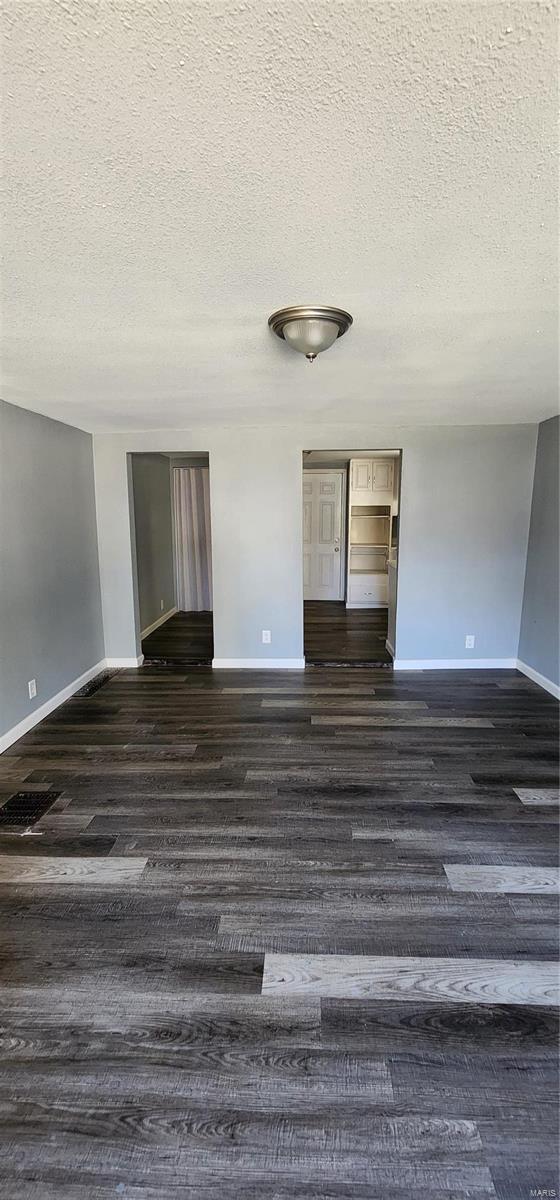 unfurnished room featuring a textured ceiling and dark wood-type flooring