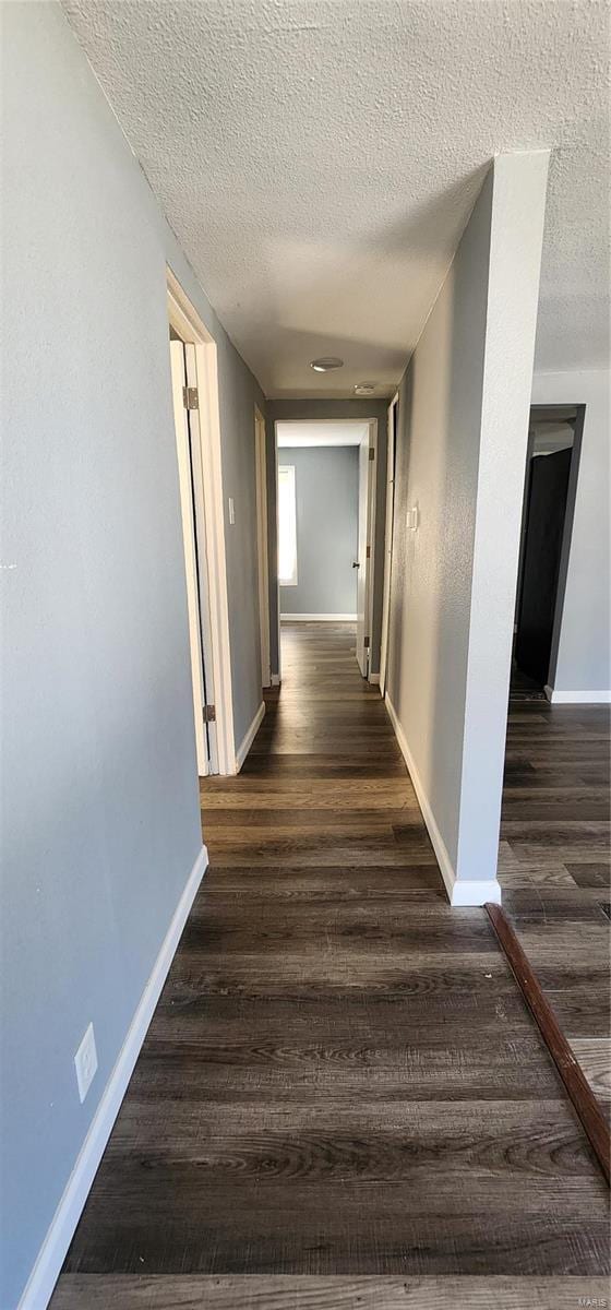 hallway featuring dark wood-type flooring and a textured ceiling