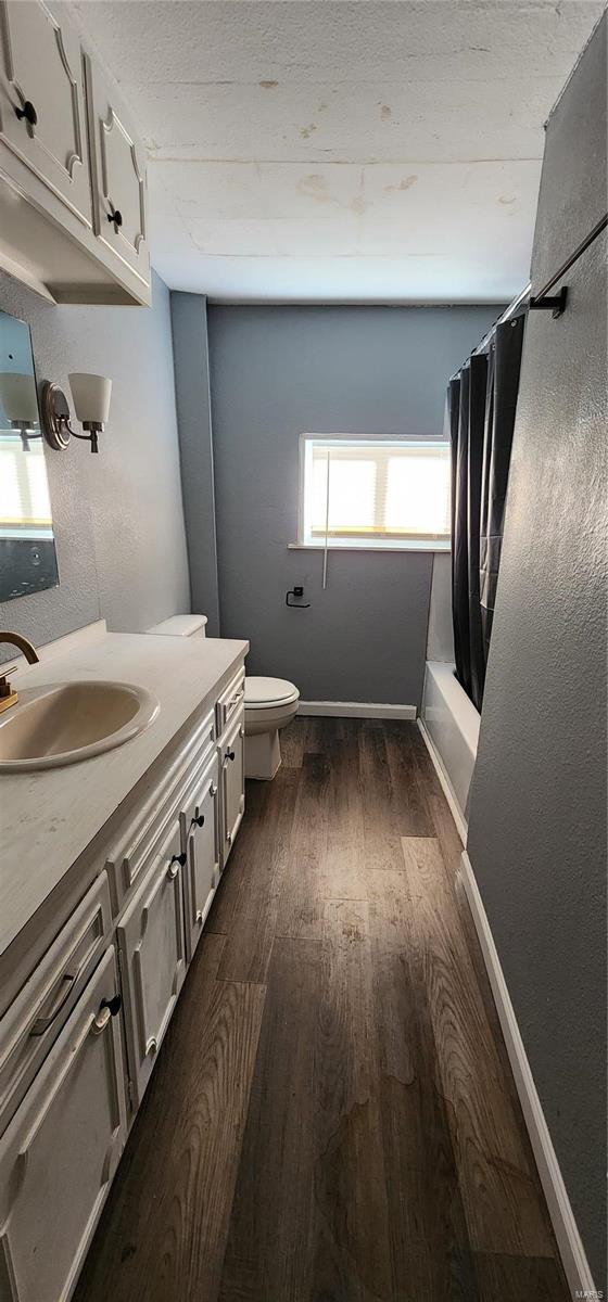 full bathroom with hardwood / wood-style flooring, vanity, toilet, and shower / bath combo