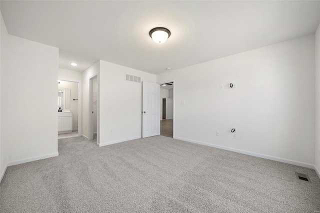 unfurnished bedroom with light carpet and connected bathroom