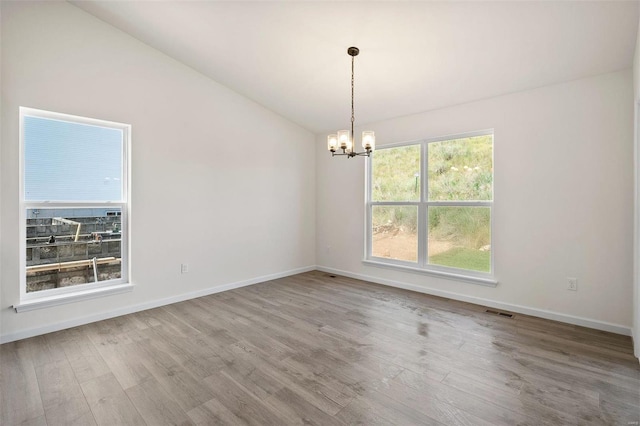 spare room featuring a chandelier, hardwood / wood-style flooring, and lofted ceiling