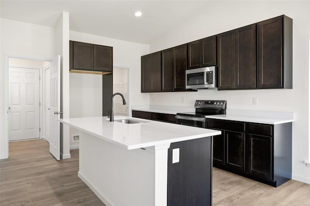 kitchen featuring light hardwood / wood-style floors, sink, an island with sink, and appliances with stainless steel finishes