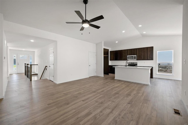 unfurnished living room featuring ceiling fan, light wood-type flooring, a wealth of natural light, and vaulted ceiling