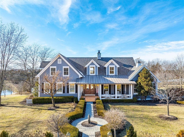 view of front of home with a chimney, metal roof, a standing seam roof, a front lawn, and a porch