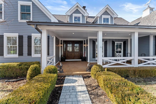 property entrance with a porch and roof with shingles