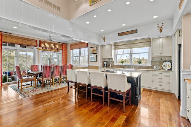 kitchen featuring light wood finished floors, a center island, a breakfast bar, and decorative backsplash