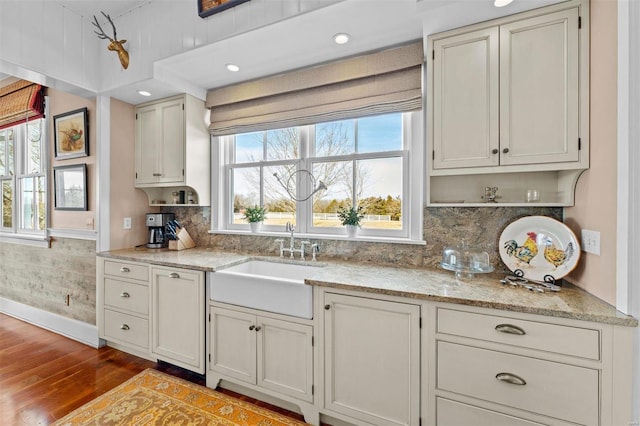 kitchen featuring light stone counters, backsplash, a sink, and light wood-style flooring