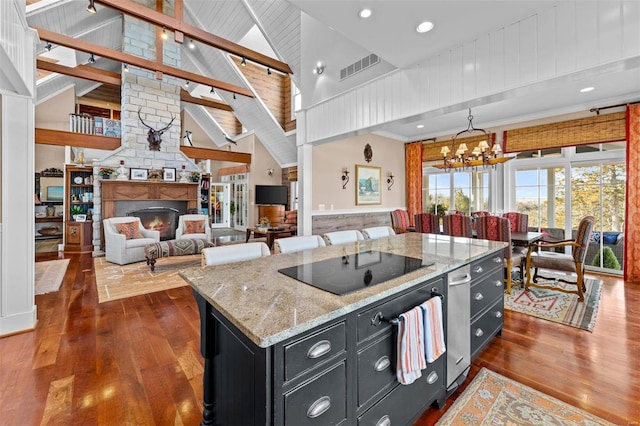 kitchen with high vaulted ceiling, black electric stovetop, a fireplace, dark cabinetry, and dark wood finished floors