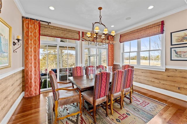 dining area with a wainscoted wall, a notable chandelier, crown molding, and wood finished floors