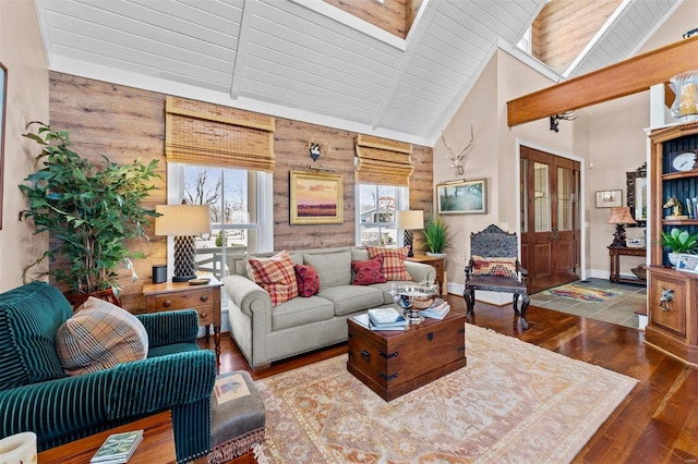 living room featuring a skylight, wood walls, high vaulted ceiling, baseboards, and hardwood / wood-style flooring