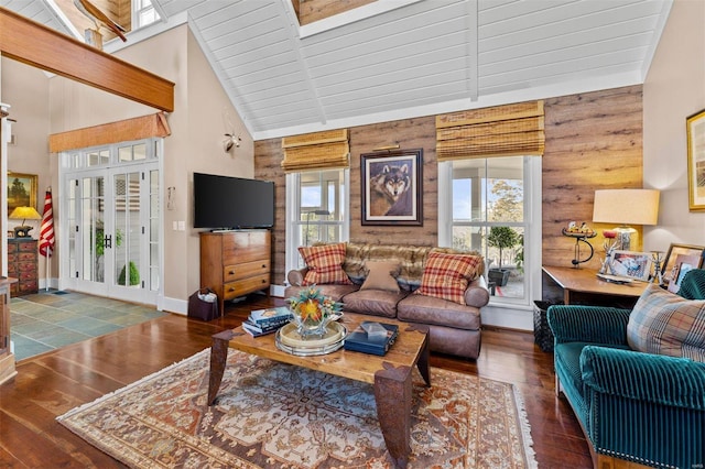 living area featuring high vaulted ceiling, hardwood / wood-style floors, wood walls, and baseboards