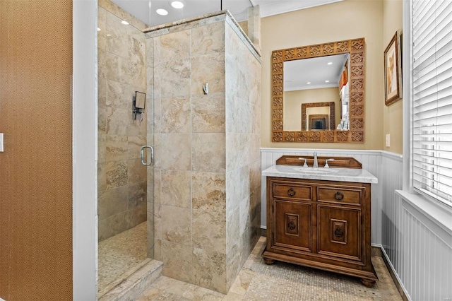 full bath featuring a wainscoted wall, a decorative wall, tiled shower, and vanity