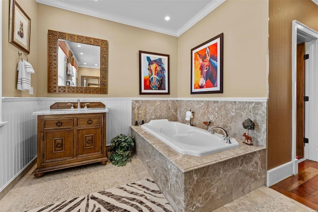 bathroom featuring a garden tub, vanity, crown molding, and wainscoting