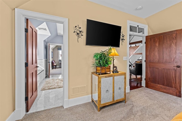 hallway featuring carpet floors, lofted ceiling, visible vents, and baseboards