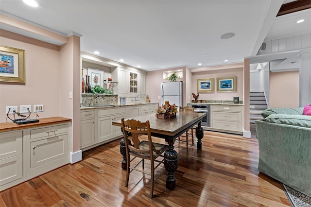 dining space featuring stairs, ornamental molding, light wood-style flooring, and recessed lighting