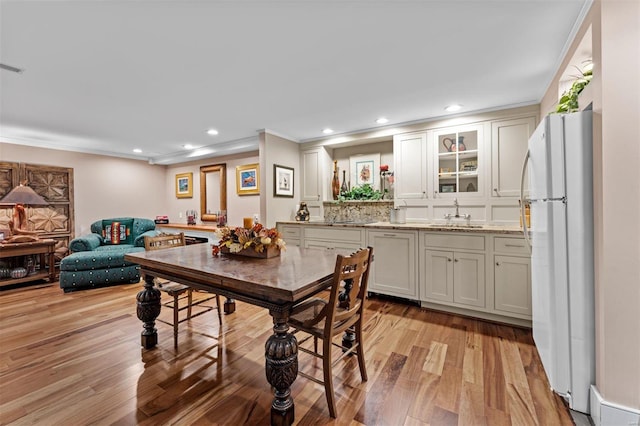 dining area featuring light wood finished floors, crown molding, and recessed lighting