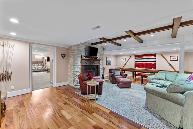 living room with light wood-style flooring, a fireplace, visible vents, baseboards, and beam ceiling