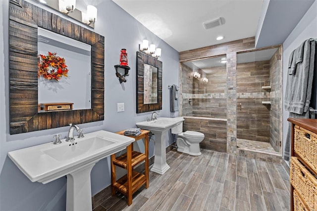 bathroom with wood finish floors, visible vents, a shower stall, and toilet