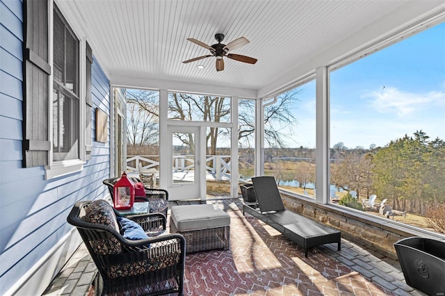 sunroom / solarium with a water view and ceiling fan