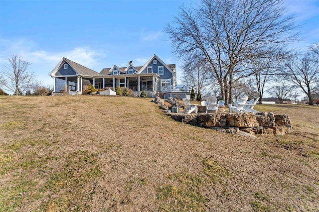 back of house featuring covered porch and a yard