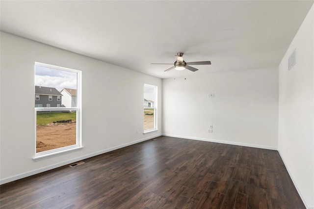 spare room featuring ceiling fan, dark wood-type flooring, and a wealth of natural light