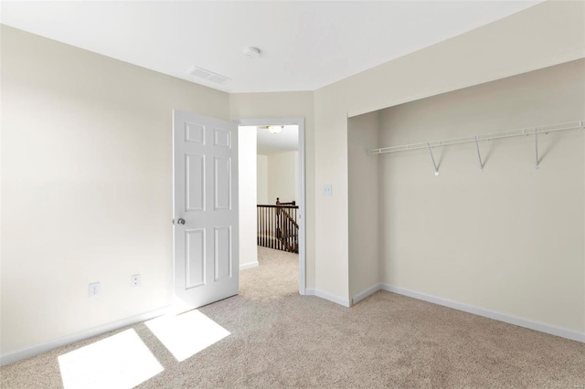 unfurnished bedroom featuring light carpet and a closet