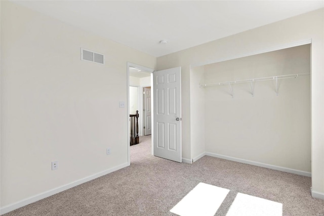 unfurnished bedroom featuring light carpet and a closet