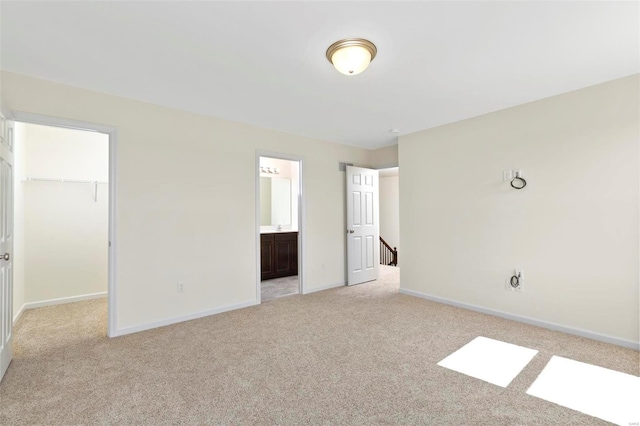 unfurnished bedroom featuring light carpet, a walk in closet, a closet, and connected bathroom