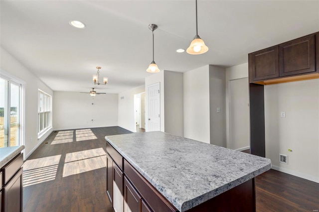 kitchen with dark brown cabinetry, ceiling fan, a center island, dark hardwood / wood-style floors, and pendant lighting