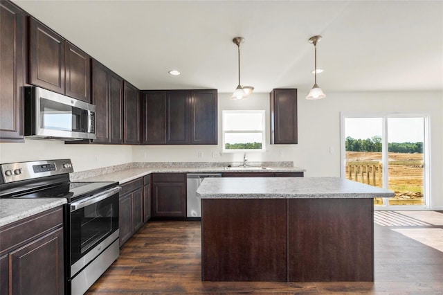 kitchen featuring dark hardwood / wood-style flooring, dark brown cabinets, stainless steel appliances, sink, and decorative light fixtures