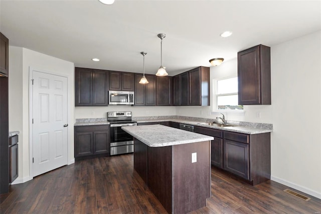 kitchen with dark brown cabinetry, sink, hanging light fixtures, a kitchen island, and appliances with stainless steel finishes