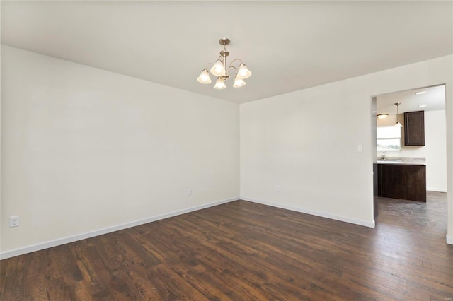 spare room with dark hardwood / wood-style floors, sink, and a chandelier