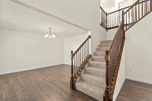 stairs featuring hardwood / wood-style floors and an inviting chandelier