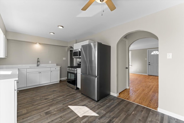 kitchen with sink, ceiling fan, white cabinetry, stainless steel appliances, and dark hardwood / wood-style flooring