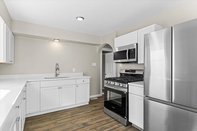 kitchen with appliances with stainless steel finishes, dark hardwood / wood-style flooring, sink, and white cabinets