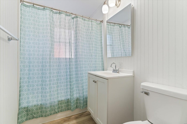 full bathroom with wooden walls, vanity, wood-type flooring, shower / bath combination with curtain, and toilet